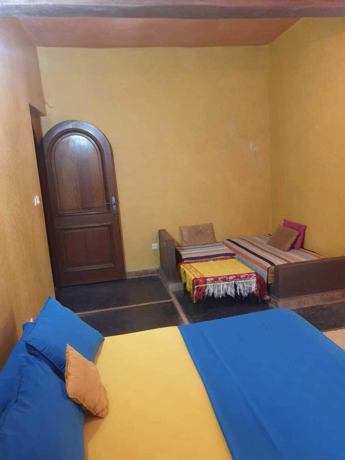Una habitación con dos camas, una puerta de madera y una pequeña mesa.