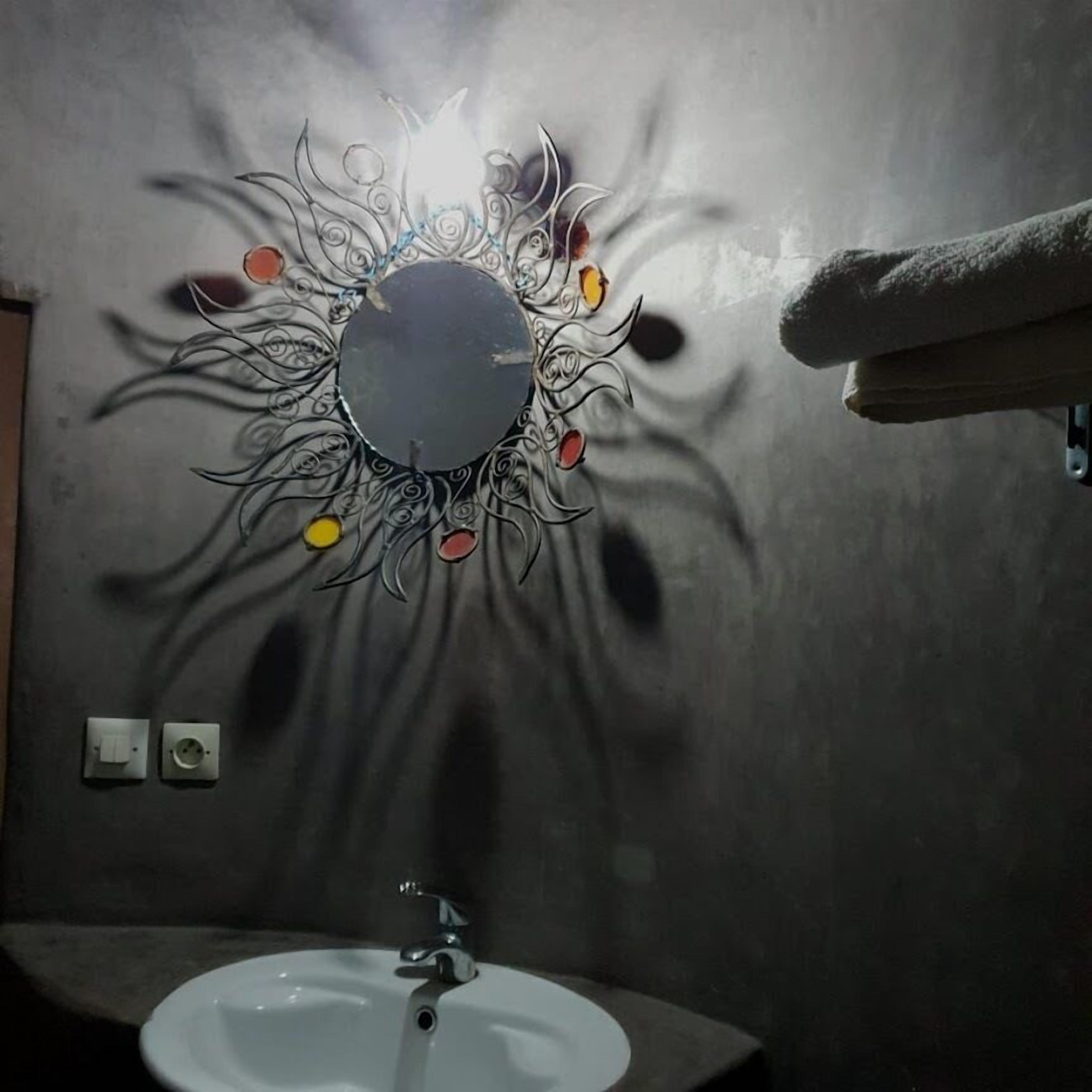 Un baño con lavamanos, espejo y toallero.