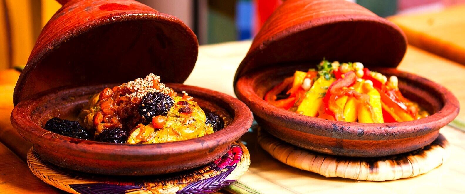 Two traditional clay pots with food, placed on woven mats.