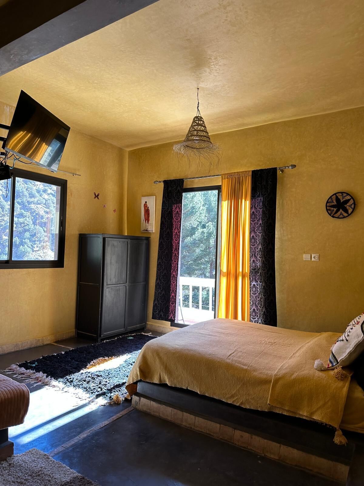 A bedroom with a bed, a wardrobe, a window, and a ceiling fan.