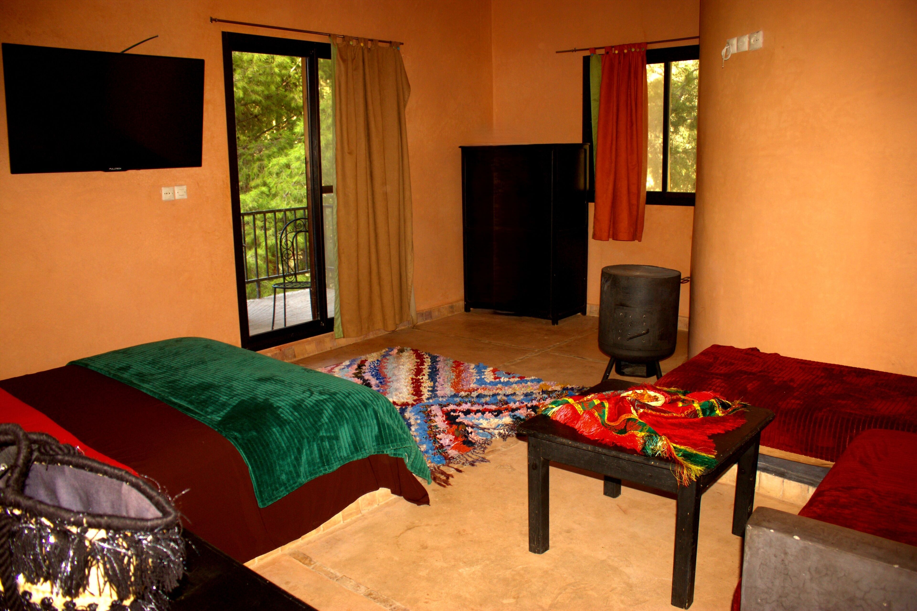 Una habitación con cama, mesa, televisión y ventana.