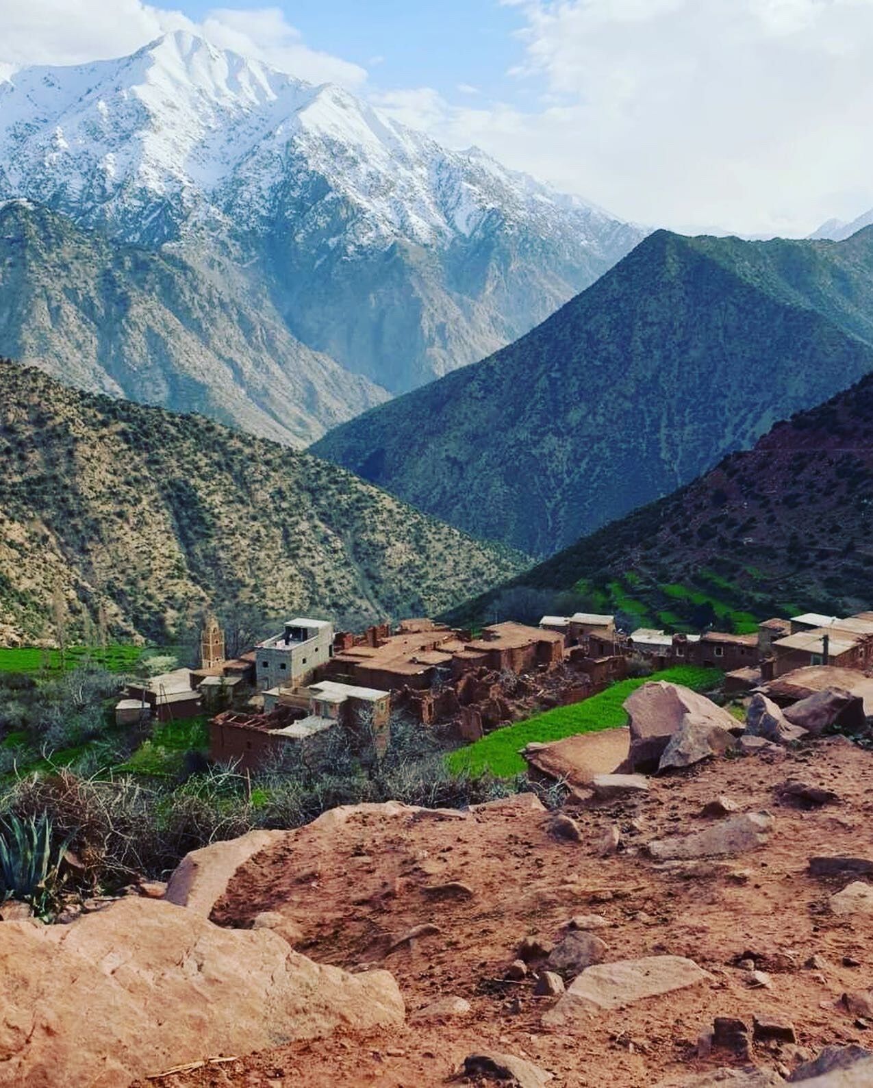 A mountainous landscape with a village featuring traditional adobe buildings.