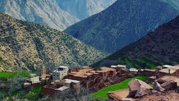 A mountainous landscape with a village featuring traditional adobe buildings.