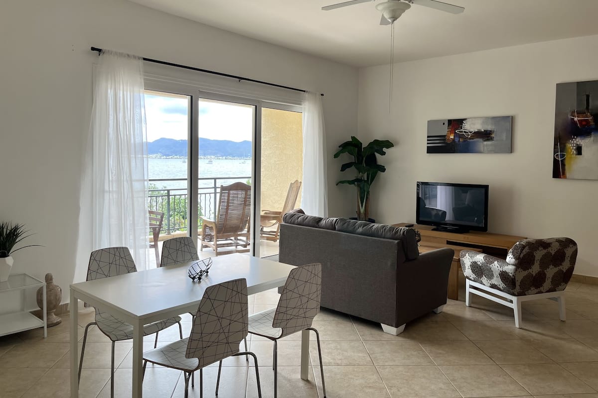Ein Wohnzimmer mit Balkon, Essbereich und Fernseher.