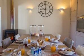 A dining table set with breakfast items, a clock, and a fireplace.