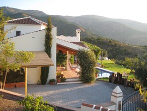Uma casa com varanda, rede e vista para as montanhas.