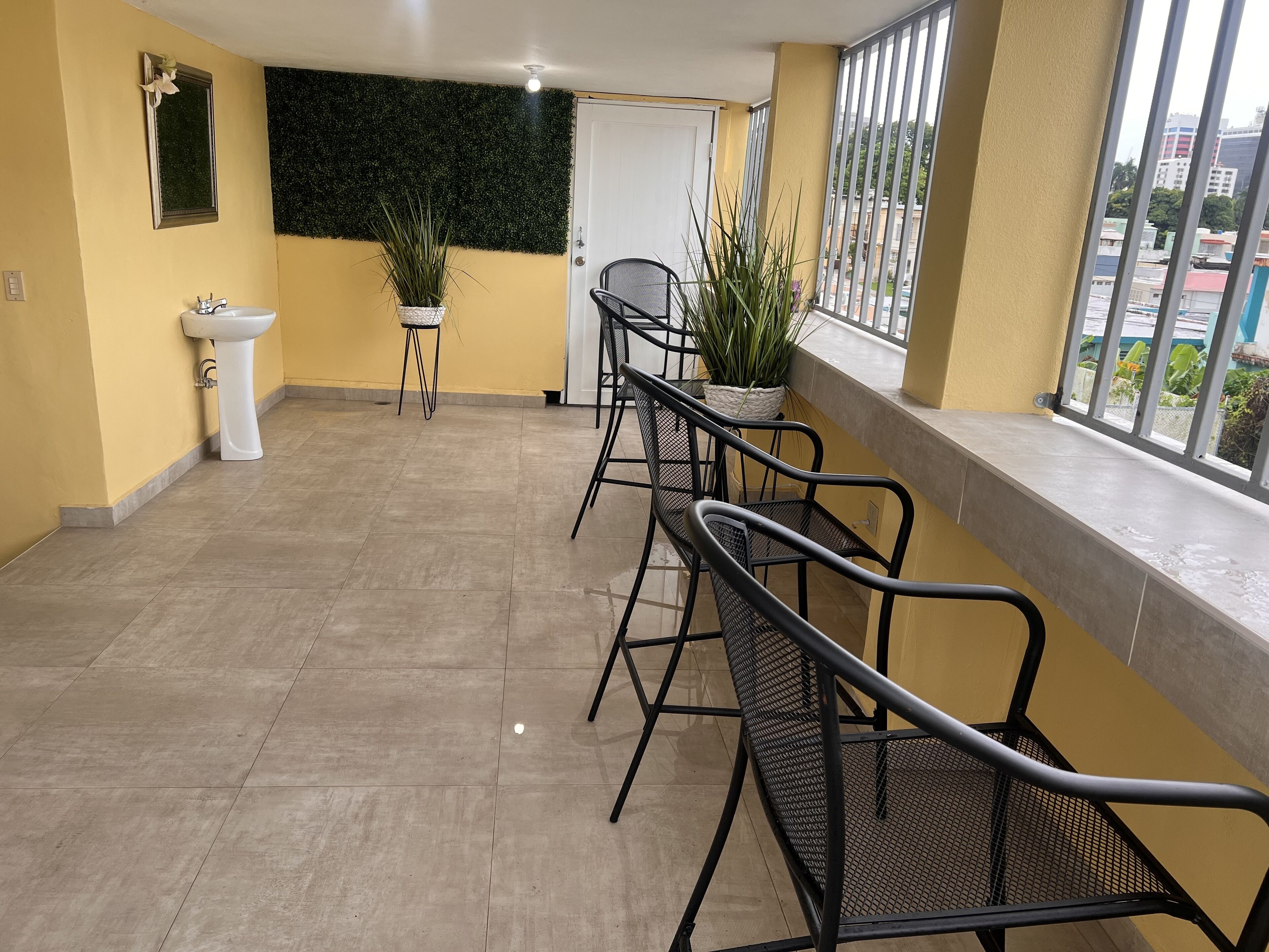 A balcony with a tiled floor, a sink, a mirror, and two chairs.
