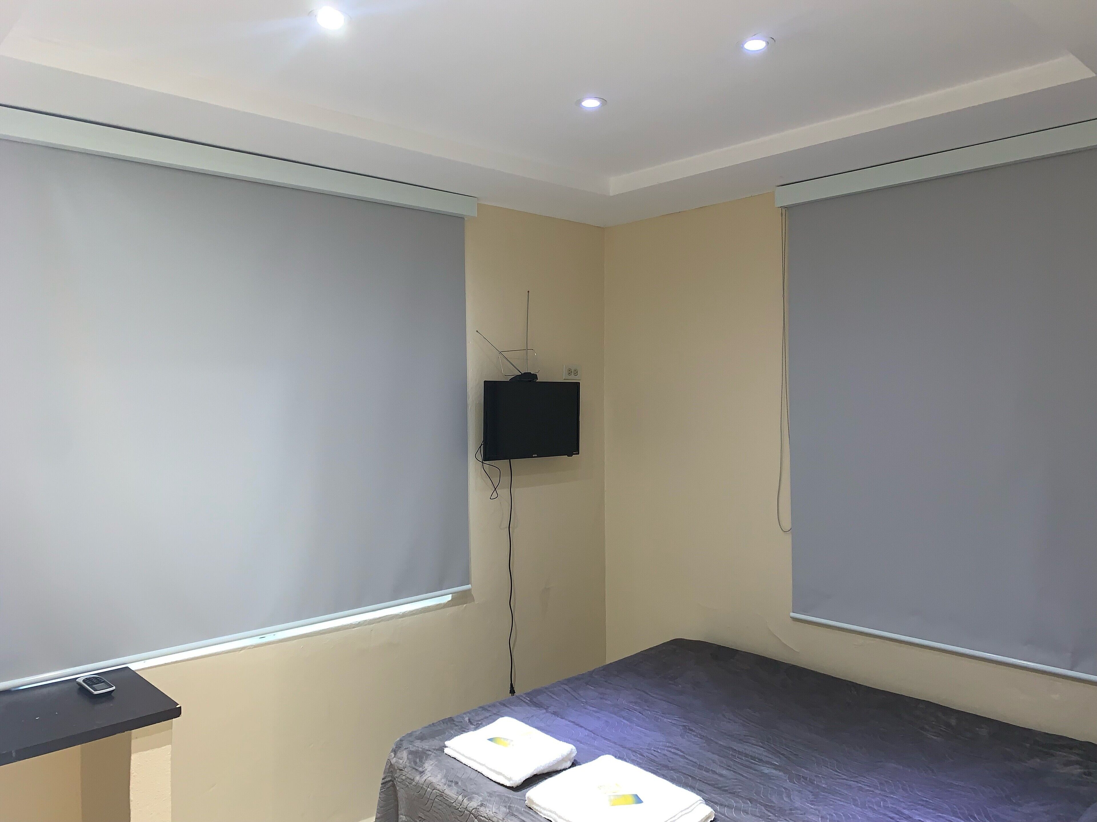 A room with a bed, a small table, and a television mounted on the wall.