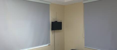 A room with a bed, a small table, and a television mounted on the wall.