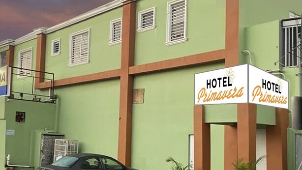 A hotel named 'Hotel Primavera' with a green facade, white signage, and a parked car. - Hospedaje Primavera (San Juan)