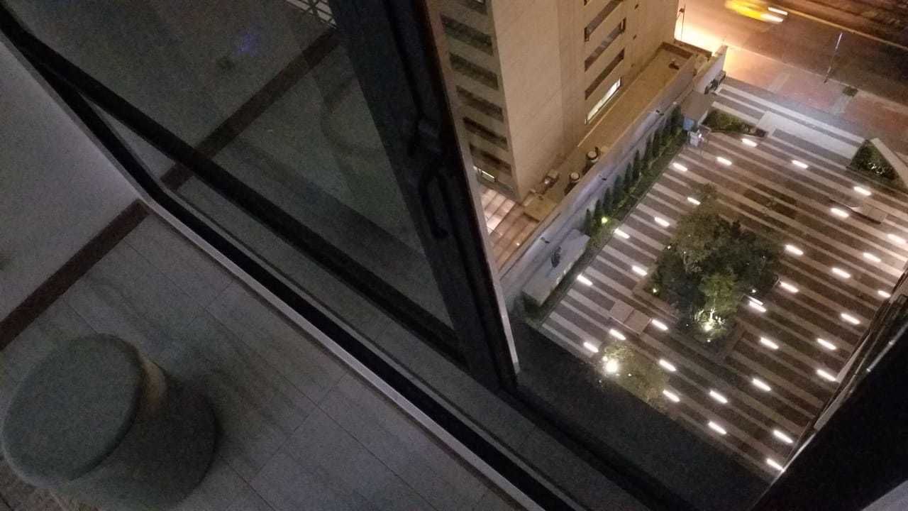 Vista de un vestíbulo de hotel con suelo de baldosas, zona de estar y una pared divisoria de vidrio.