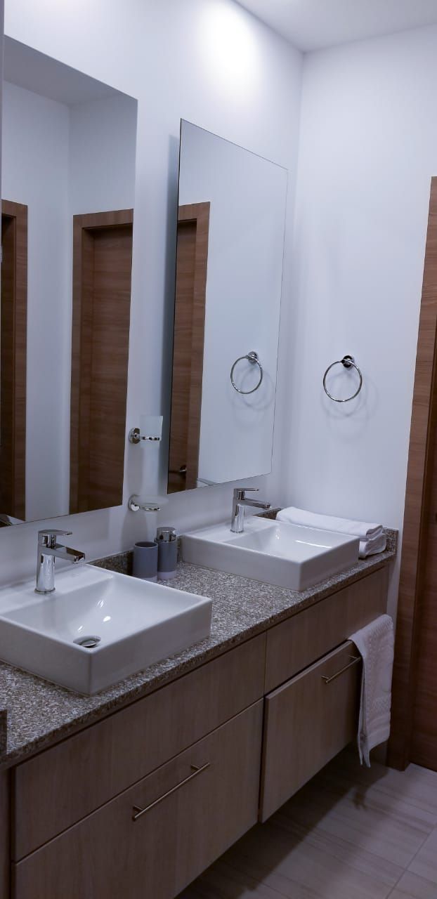 A modern bathroom with two sinks, large mirrors, and wooden cabinets.
