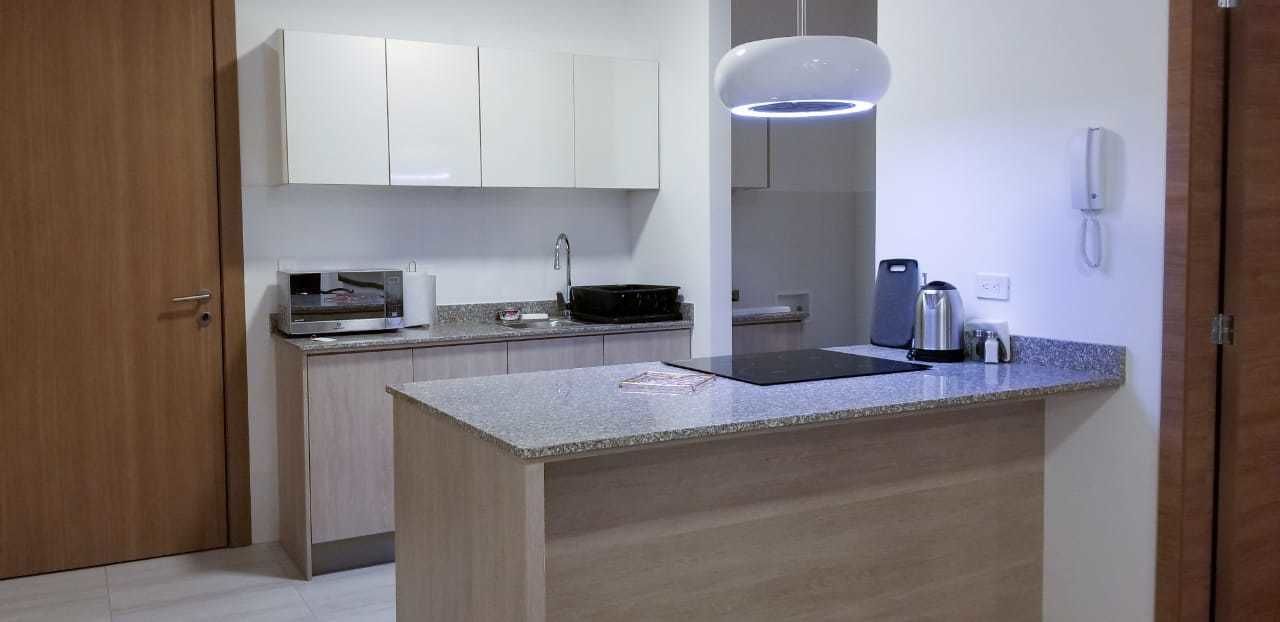 A modern kitchen with a granite countertop, white cabinets, and a built-in microwave.