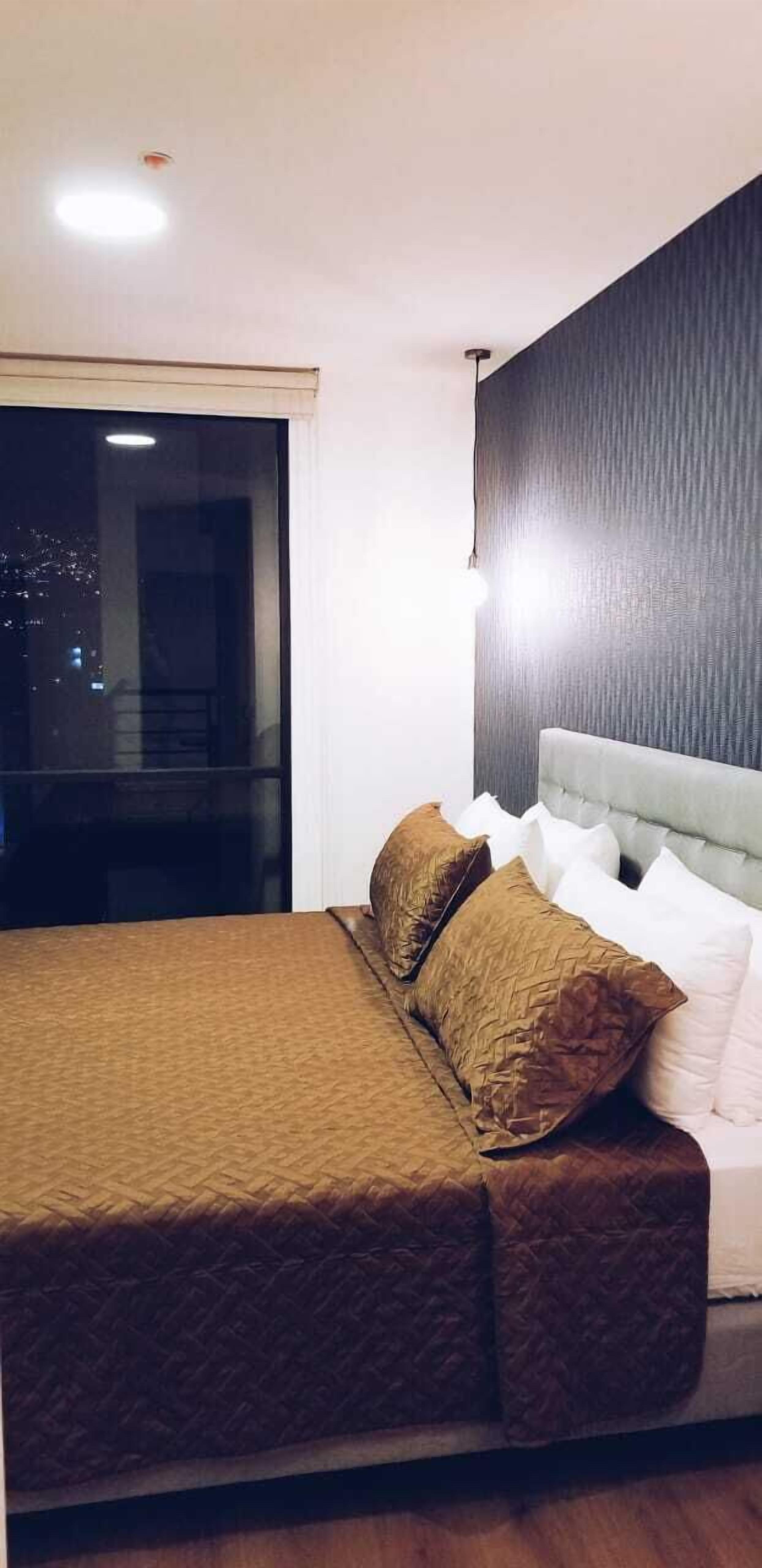 Un dormitorio con cama, ventana y pared con textura.