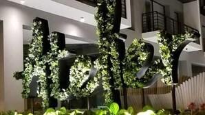 A hotel entrance with a large illuminated sign, a multi-story building, and a landscaped garden area. - Luxury apartments Quito (Quito)