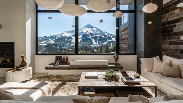 A modern living room with a large window overlooking a snow-capped mountain. - Lone Peak Views | Hot Tub | Ski-In/Out (Big Sky)