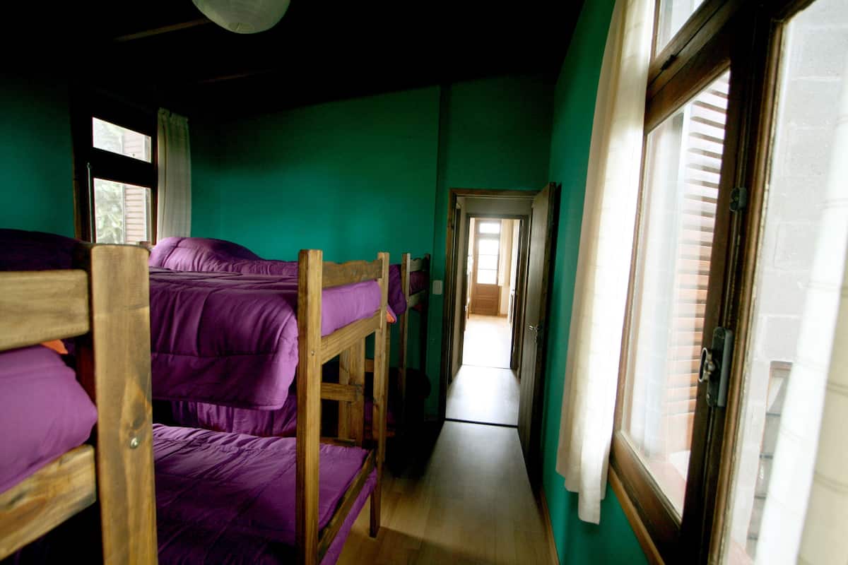 Ein Zimmer mit Etagenbetten, einem Flur und einer Tür zu einem weiteren Zimmer.