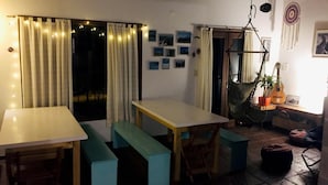 Una stanza accogliente con un tavolo di legno e panche, un'amaca e una chitarra.