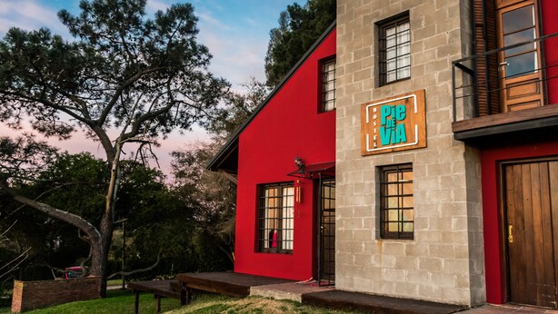 Un edificio rosso con un cartello che riporta la scritta "Pie de Via Hostel".