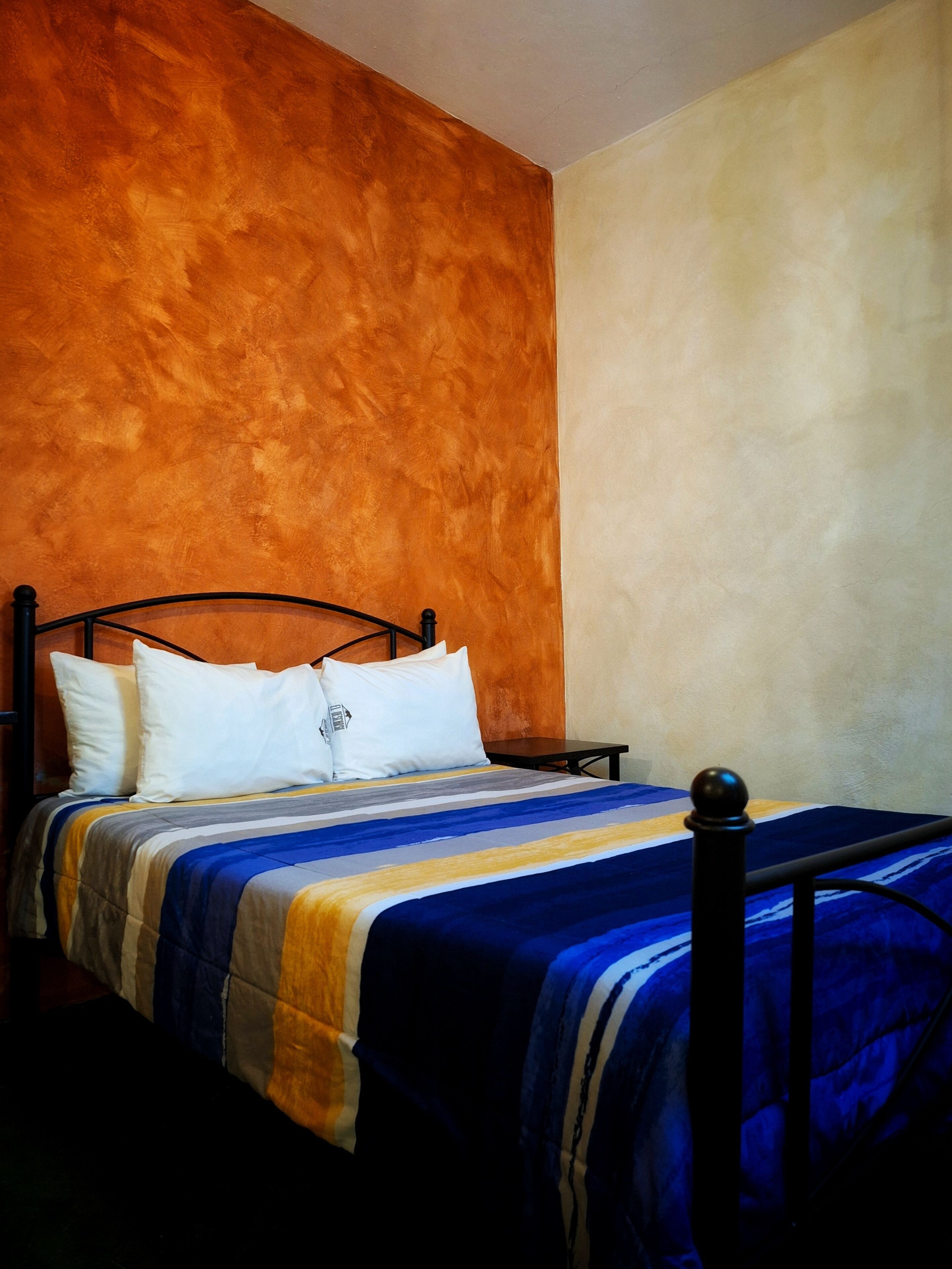 A single bed with a metal frame, white pillows, and a striped bedspread.