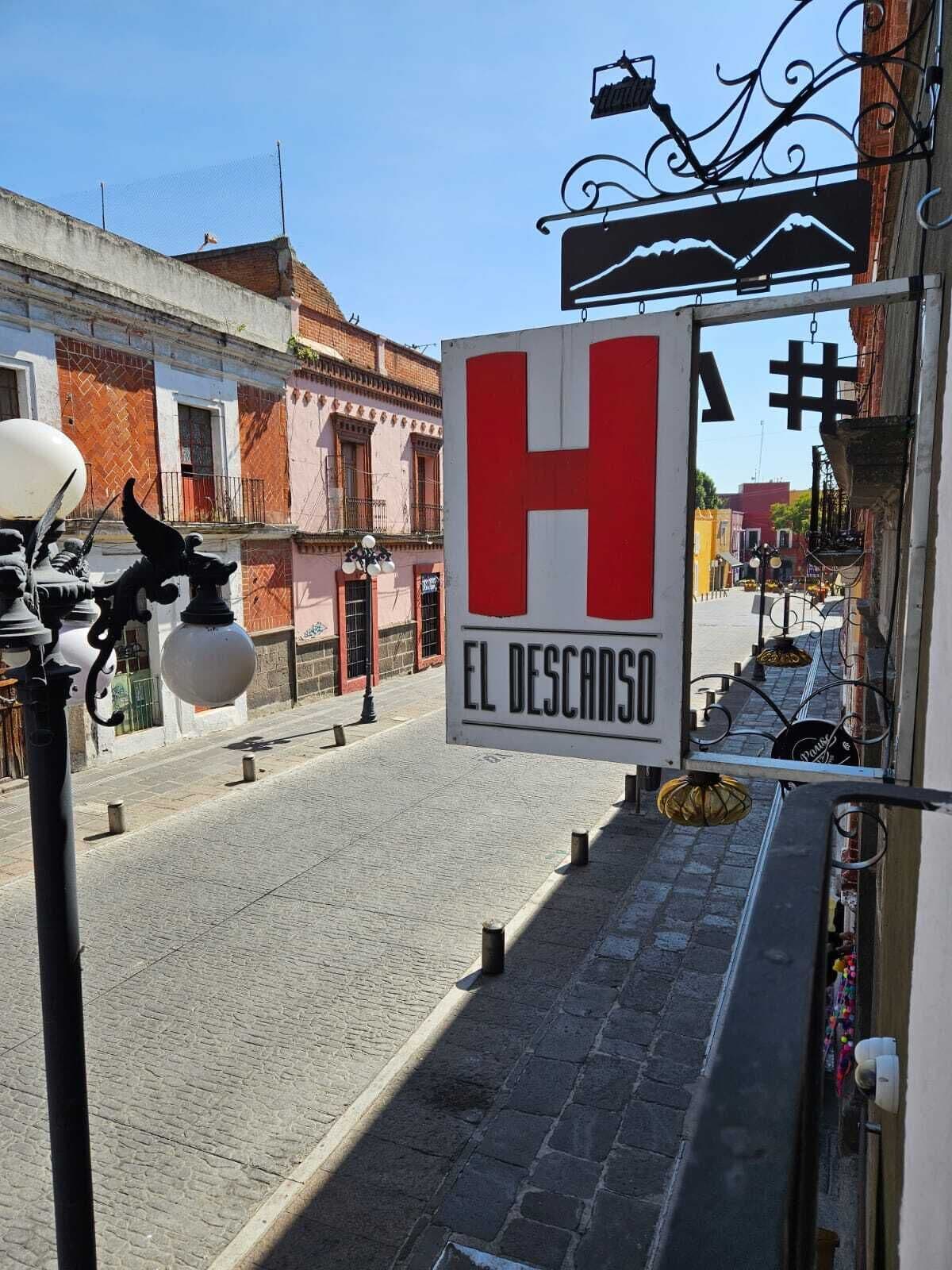 A street view with a prominent red and white sign for 'El Descanso' hotel.