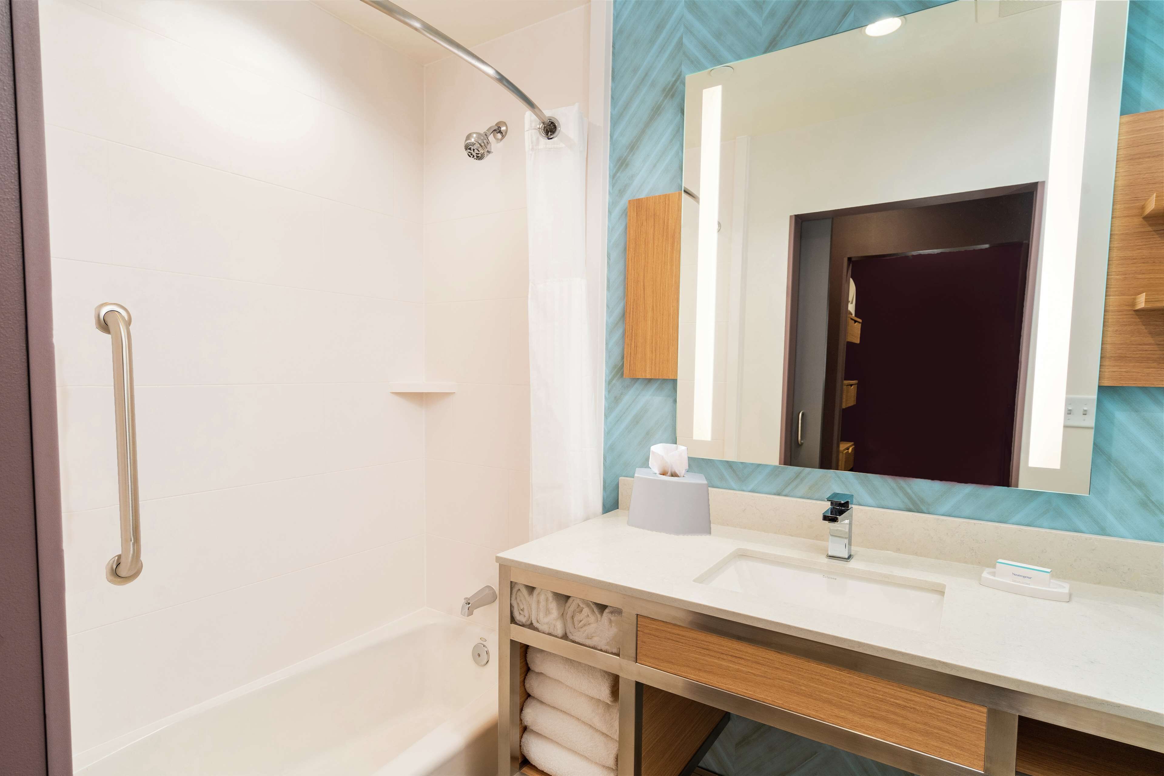 A modern bathroom with a walk-in shower, a vanity with a mirror, and a towel rack.