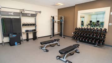 Et fitnesscenter med vægttræningsudstyr, bænke og håndvægte.
