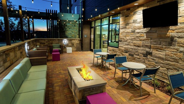 An outdoor patio with stone walls, a fire feature, seating, and a TV mounted on the wall. - Hilton Garden Inn Cedar Park Austin (Austin)