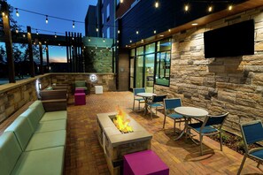 An outdoor patio with stone walls, a fire feature, seating, and a TV mounted on the wall. - Hilton Garden Inn Cedar Park Austin (Austin)