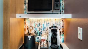 A kitchenette with a microwave, coffee maker, and coffee pods.