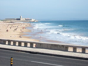 Une plage séparée de la route par une barrière en béton.