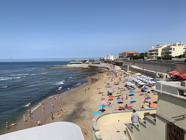 Une plage avec des parasols, des chaises longues et des gens qui profitent de la mer.