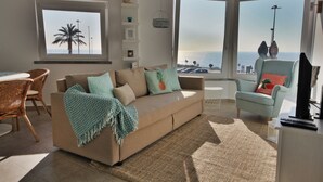 Una sala de estar con sofá, sillones, una mesa de comedor y vista al mar.