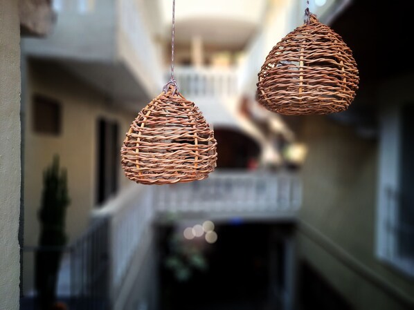 Two wicker pendant lights hanging in a corridor with a blurred background of a building facade.
