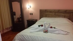 A neatly made bed with a heart-shaped towel arrangement and a small decorative item on the pillows. - Hotel Nichkito (Uyuni)