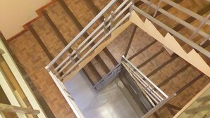 A spiral staircase with a metal railing, wooden steps, and a glass elevator door. - Hotel Nichkito (Uyuni)