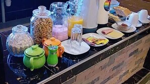 A breakfast buffet setup with various food items and beverages. - Hotel Nichkito (Uyuni)