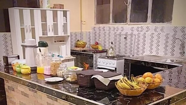 A kitchen with a tiled backsplash, a stove, and various food items on the counter. - Hotel Nichkito (Uyuni)