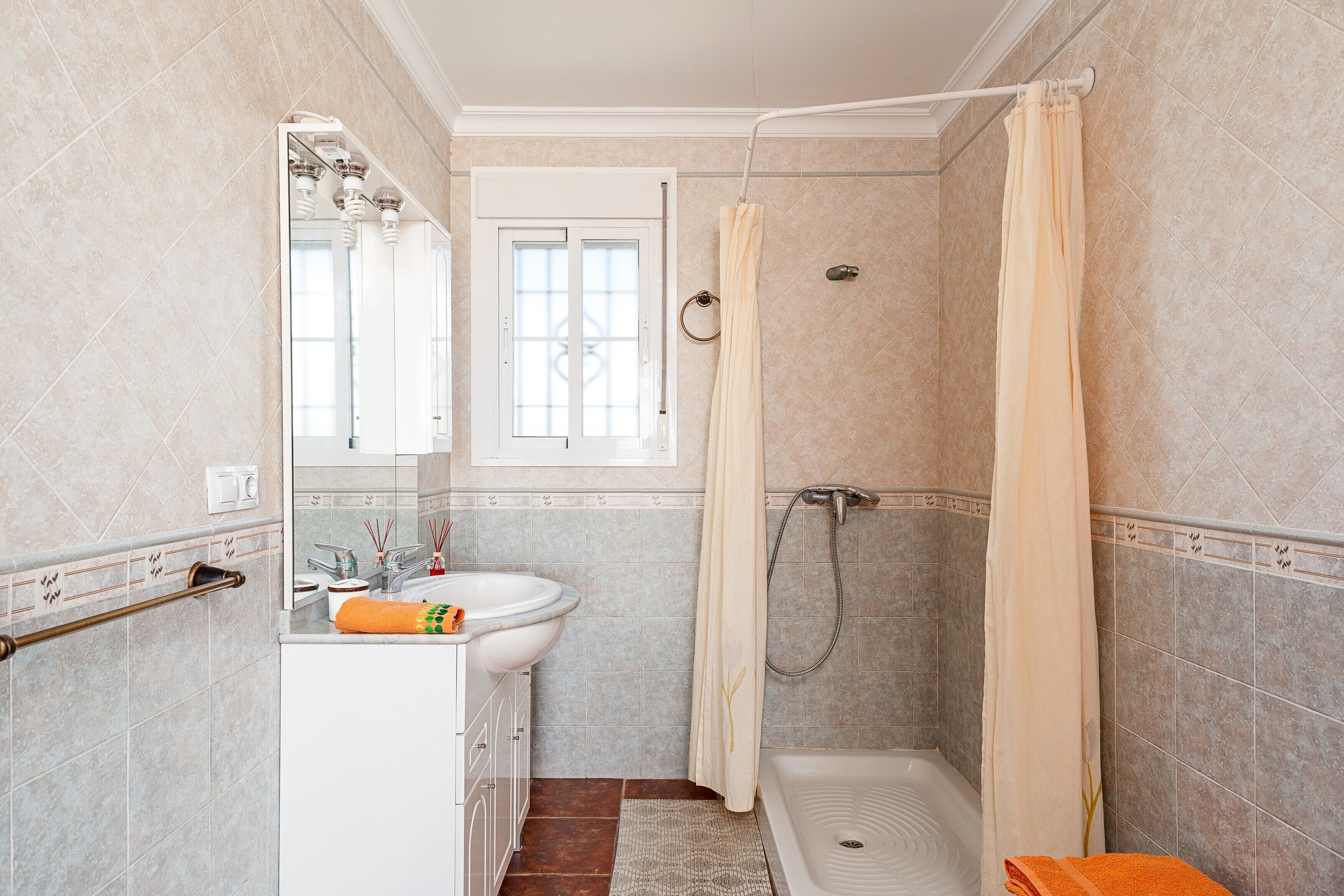 Een badkamer met douche, wastafel en spiegel.