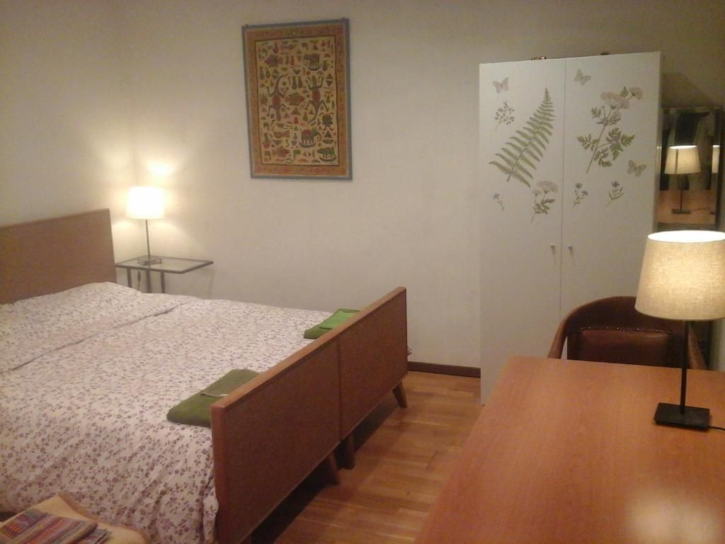Ein Schlafzimmer mit Bett, Schreibtisch, Stuhl, Kleiderschrank und einer Wandlampe.