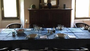 Ein Esszimmer mit einem langen Tisch, gedeckt für vier Personen, an beiden Seiten zwei Fenster.