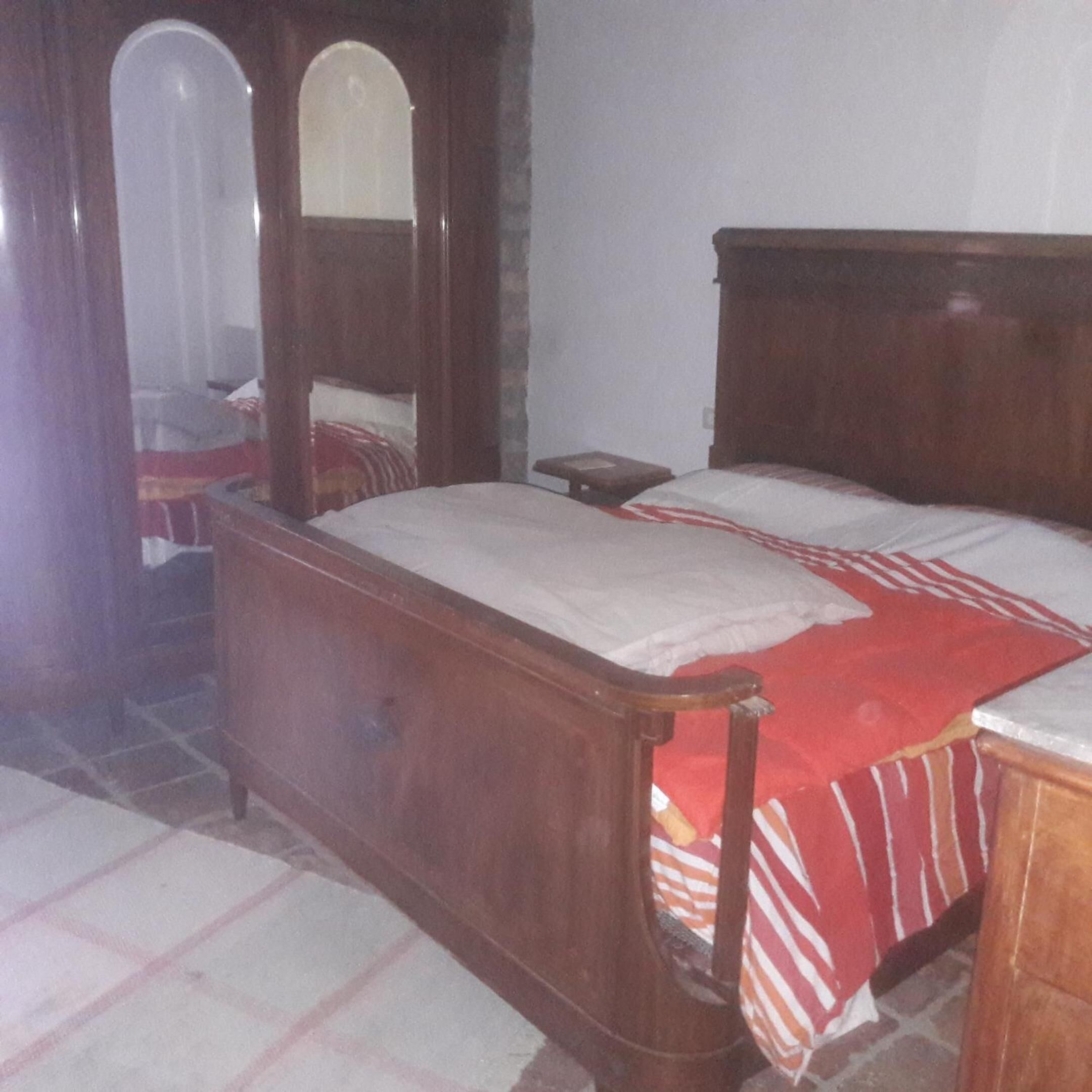 A bedroom with a wooden bed, a nightstand, and a mirror.