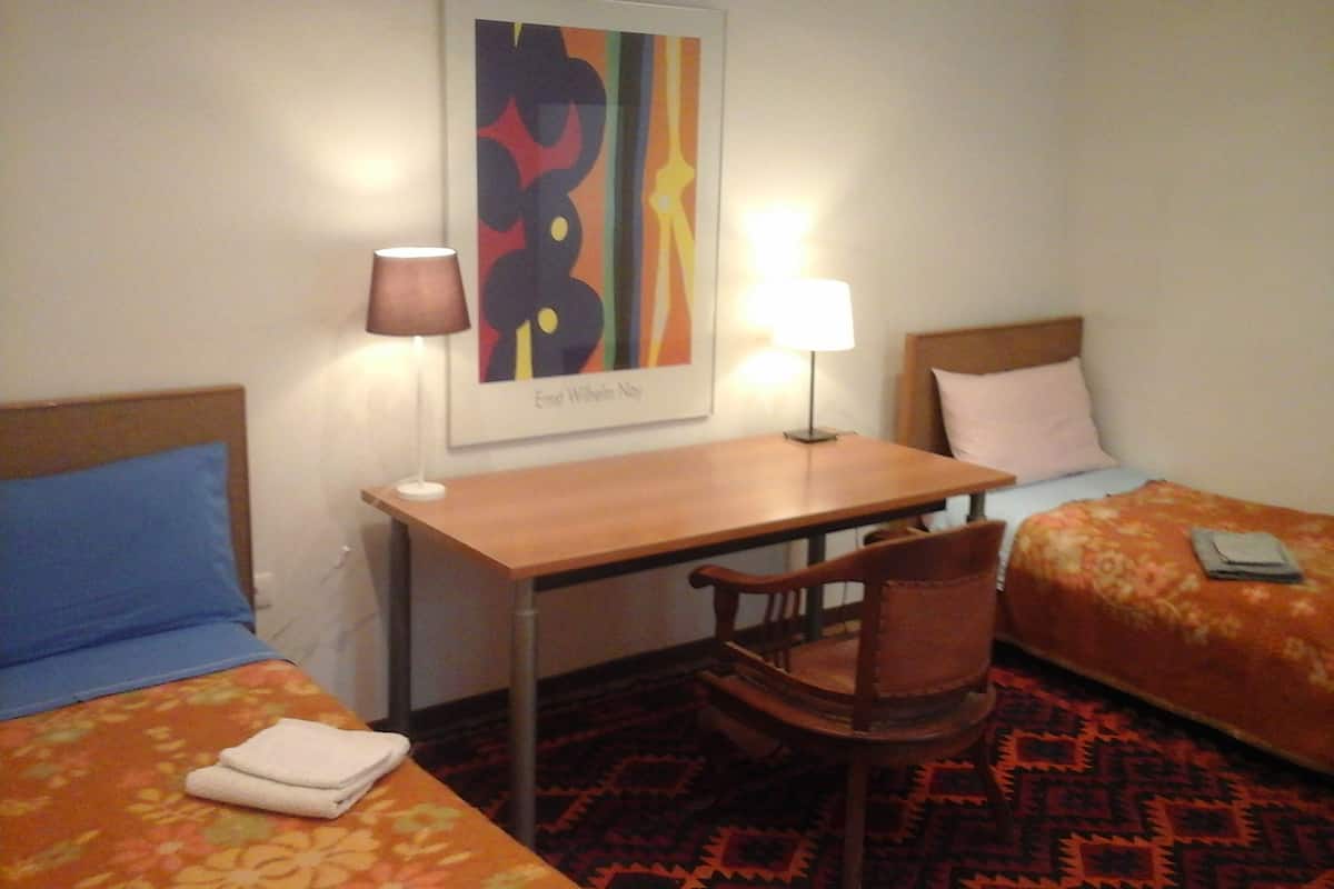 Ein Hotelzimmer mit zwei Betten, einem Schreibtisch, einem Stuhl und zwei Lampen.