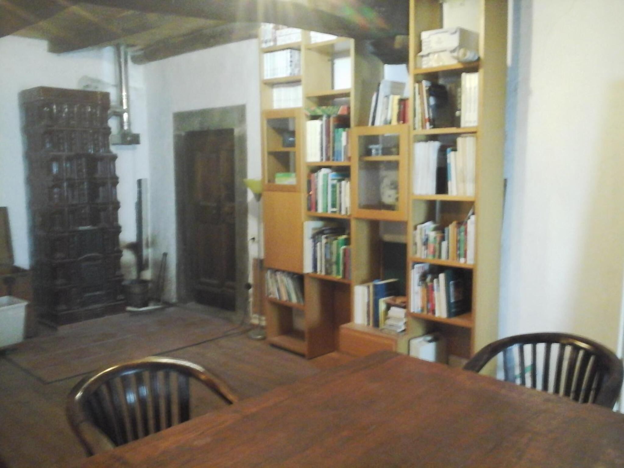 Um quarto com uma mesa e cadeiras de madeira, uma estante cheia de livros e um armário de madeira grande.