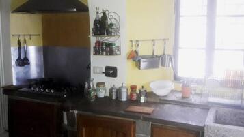 Una cocina con estufa, horno y un tendedero con botellas y frascos.