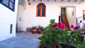 Un patio con plantas en macetas y una escalera que lleva a una puerta.