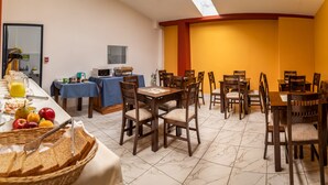 Un bufé de desayuno con diversas opciones de comida y una zona de estar con sillas y mesas de madera.
