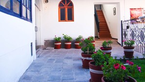 Un patio con una escalera que conduce a un nivel superior, plantas en macetas y una ventana con marco de madera.