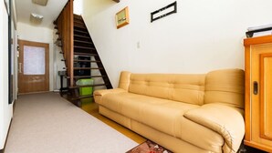 Un salon avec un canapé beige, un meuble en bois et un escalier.