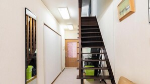 Un couloir étroit avec un escalier en bois menant à un palier.